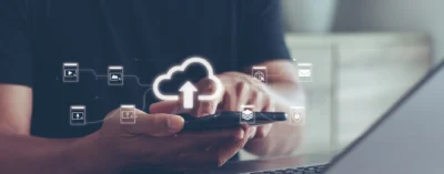 Hands holding phone with cloud upload icons.
